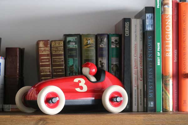 Wooden Toy Race car sitting on a book shelf with books.