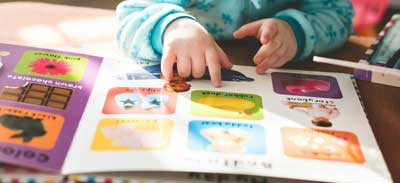child fingers pointing to images in a picture book