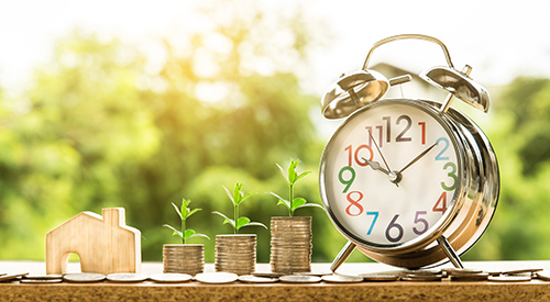 Alarm Clock with Stack Coins and wood house on table
